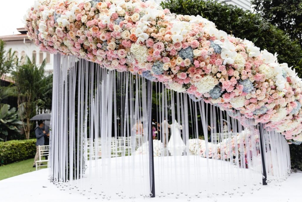 Bride and groom at Raffles Hotel Singapore outdoor wedding ceremony surrounded by 82000 stems of flowers ~ luxury wedding by Create Your Story
