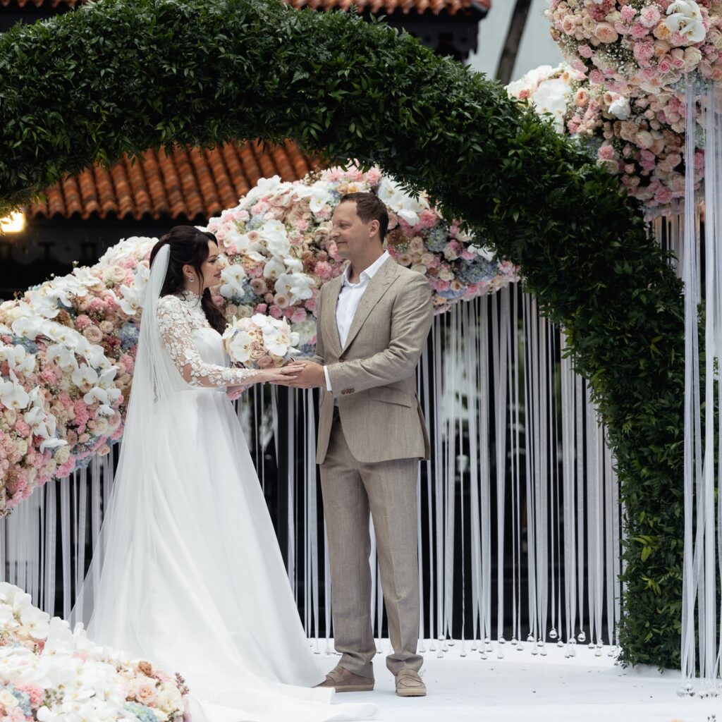 Wedding couple portrait at Raffles Hotel Singapore surrounded by extraordinary floral installation ~ luxury destination wedding by Create Your Story ~ photography by Yulikov